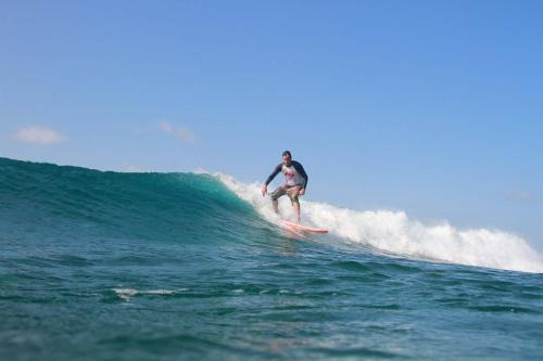 a man riding a wave on a surfboard in the ocean at Aasna Inn in Thulusdhoo