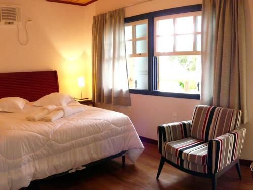 a bedroom with a bed and a chair and a window at Pouso da Chica in Diamantina