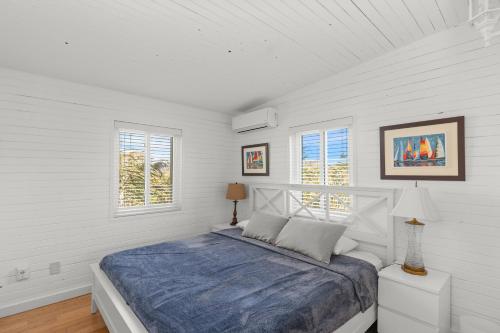 een witte slaapkamer met een bed en 2 ramen bij 10 Cayuga in Ocean Bay Park