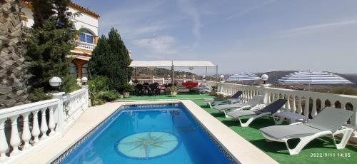 una piscina en el balcón de una casa con sillas y mesa en Huerta Bonela, en Casarabonela