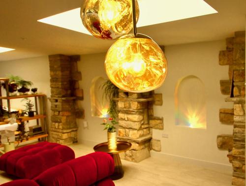 a living room with a red couch and two lights at The Old Poolhouse in High Bentham