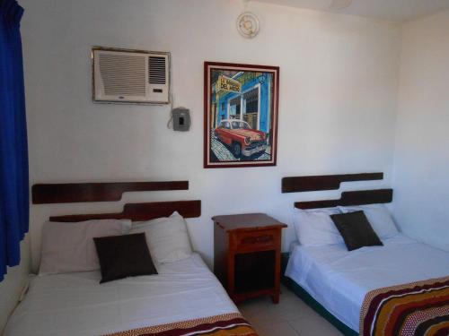 a bedroom with two beds and a picture of a car on the wall at Hotel y Bungalows Monteverde in Chachalacas