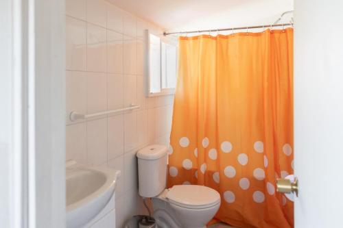 baño con cortina de ducha naranja y aseo en La Casona, baño Compartido, en Villa Cerro Castillo