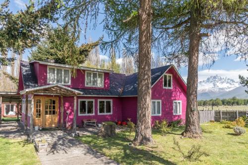 a pink house with trees in front of it at La Casona, baño Compartido in Villa Cerro Castillo