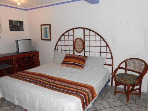 a bedroom with a bed and a chair at Hotel y Bungalows Monteverde in Chachalacas