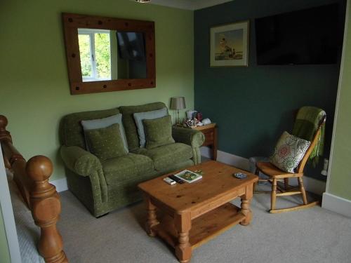 a living room with a green couch and a table at The Mill at Glynhir in Ammanford