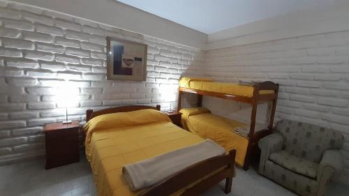 a small bedroom with two beds and a chair at HOTEL CAASAMA in Santa María