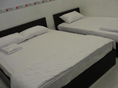 two beds in a room with white sheets at Khoa Phu Hotel in Can Tho