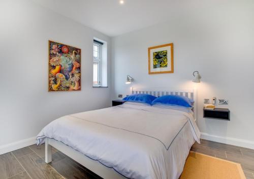 um quarto branco com uma cama grande e almofadas azuis em Morannedd em Aberdaron