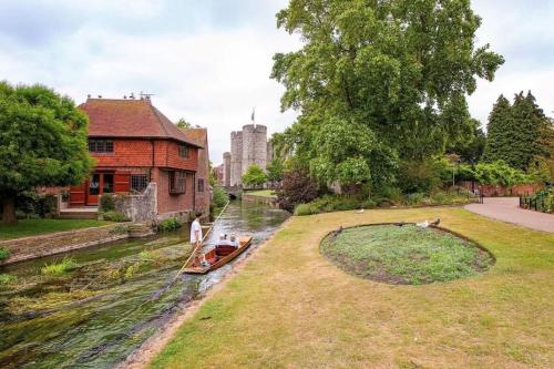 a small boat in a river next to a building at Centrally Located a Home from Home - Free Parking in Kent