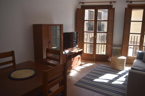a living room with a tv and a table and windows at Puerta del Hierro in Sigüenza