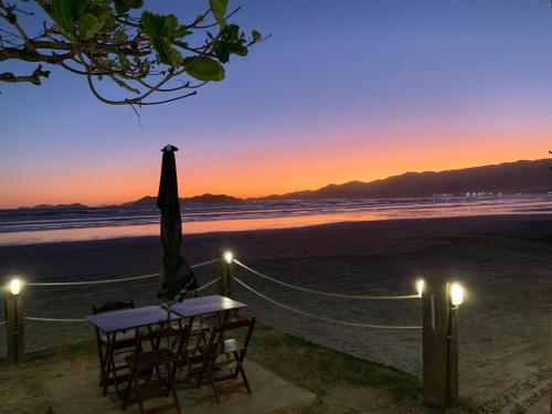 stół i krzesła na plaży o zachodzie słońca w obiekcie Pousada Jolly Roger w mieście Bertioga