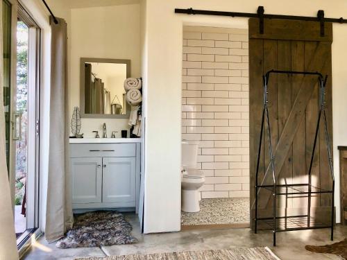 a bathroom with a toilet and a sliding barn door at NEW Feather Your Nest King bed Casita, Balcony/BBQ, Amazing views & great Location! Dog friendly in Prescott