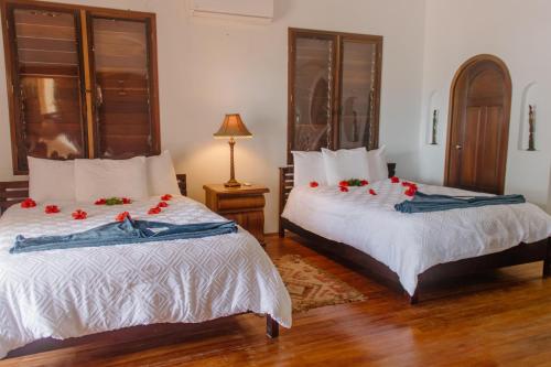 1 dormitorio con 2 camas con rosas rojas. en La Perla del Caribe - Villa Amber, en San Pedro