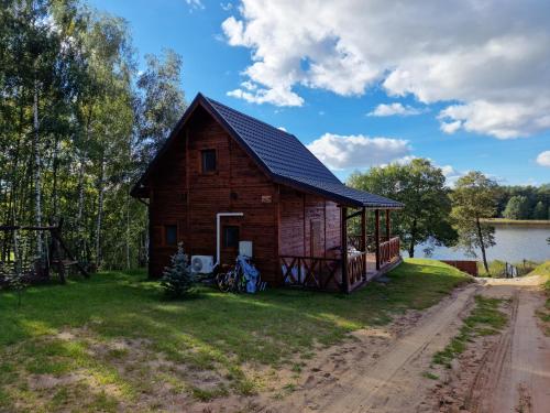 a small wooden cabin on the side of a lake at Domek Letniskowy, Dom Całoroczny Eryś 80m2. Przy Plaży. Wynajem. Odpoczynek in Książki