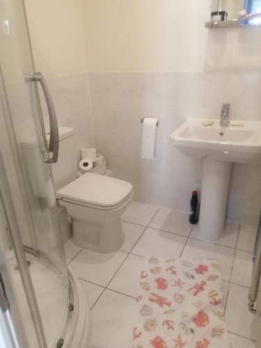 a white bathroom with a toilet and a sink at Maidstone Homestay in Boxley