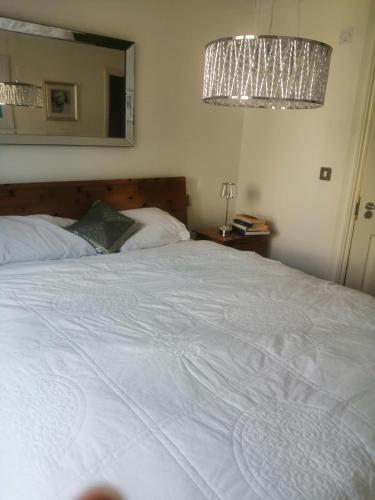 um quarto com uma grande cama branca e um lustre em Maidstone Homestay em Boxley