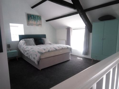 a bedroom with a bed and two windows and a staircase at Pandy cymunod in Bryngwran