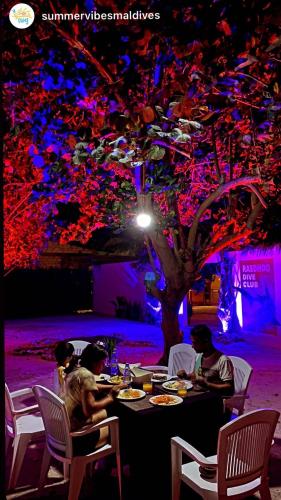 a group of people sitting at a table with food at Summer Vibes Beach Front in Rasdu