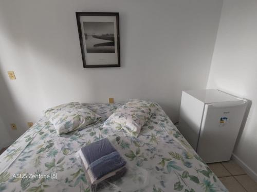 - une chambre avec un lit et une photo sur le mur dans l'établissement Flat Aconchegante na Orla de Camburi, à Vitória