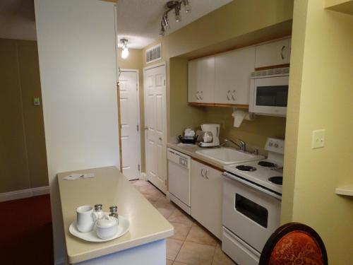 a kitchen with white cabinets and a white stove top oven at Suites at Jockey Club (No Resort Fee) in Las Vegas