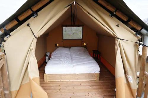 a bedroom in a tent with a bed in it at Luxe en romantische overnachting voor 2 in Behelp