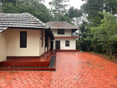 ein kleines Haus mit einer roten Backsteineinfahrt in der Unterkunft Deesha Homes in Wayanad