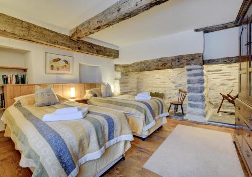 a bedroom with two beds and a stone wall at Ysgubor Newydd in Machynlleth