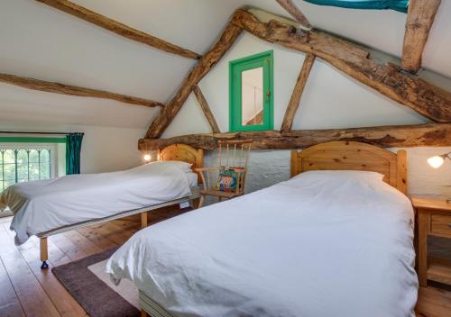 two beds in a room with wooden beams at Stabal Pant y Lludw in Machynlleth