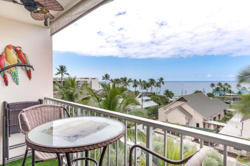 a balcony with a table and chairs and a view of the ocean at Kailua Village Resort 605 in Kailua-Kona