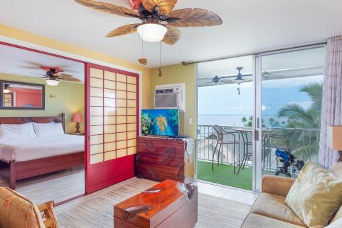 a bedroom with a bed and a balcony with the ocean at Kailua Village Resort 605 in Kailua-Kona