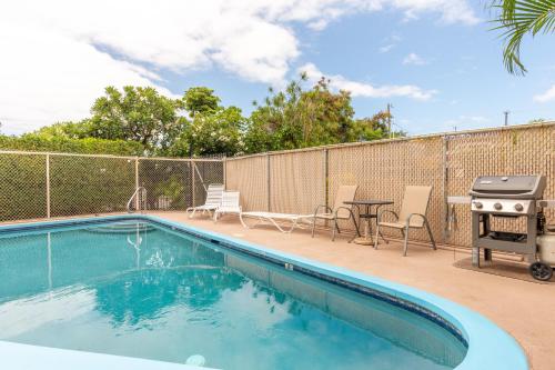 a swimming pool with a grill and a table and chairs at Kailua Village Resort 605 in Kailua-Kona