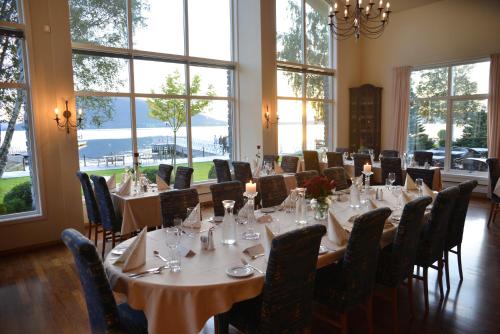 a dining room with tables and chairs and windows at Rosendal Fjordhotel in Rosendal