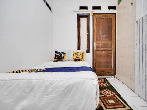 a bedroom with a bed and a wooden door at SPOT ON 91775 Pondok 14 Syariah in Bandung