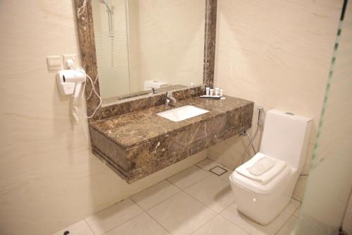 a bathroom with a sink and a toilet and a mirror at Broad Almkan Apart Hotel in Taif