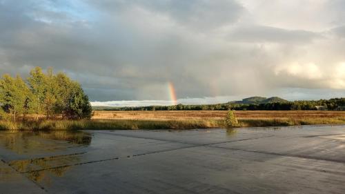 um arco-íris no céu sobre um campo com um rio em Ralsko - Hradčany em Hradčany