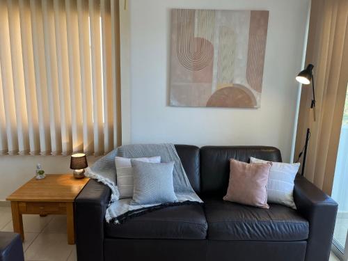 uma sala de estar com um sofá de couro preto com almofadas em Beautiful 2 Bed Apartment in Peyia Valley, Paphos em Peyia
