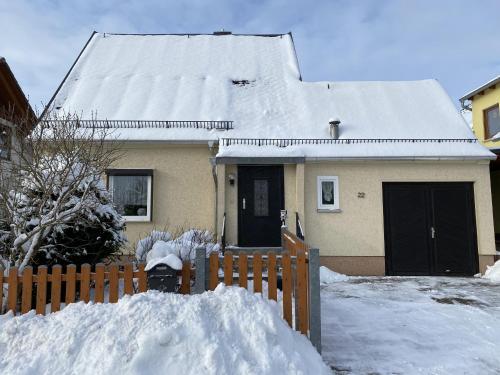 une maison avec une clôture et un tas de neige dans l'établissement Ferienhaus Auerswalde, à Lichtenau