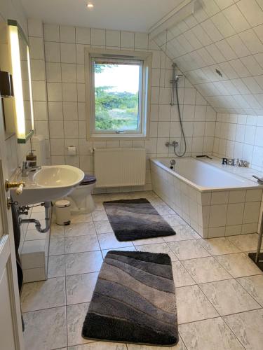 ein Badezimmer mit einer Badewanne, einem Waschbecken und einer Badewanne in der Unterkunft Freistehendes Einfamilienhaus mit Boddenblick Nähe Ostsee in Fuhlendorf
