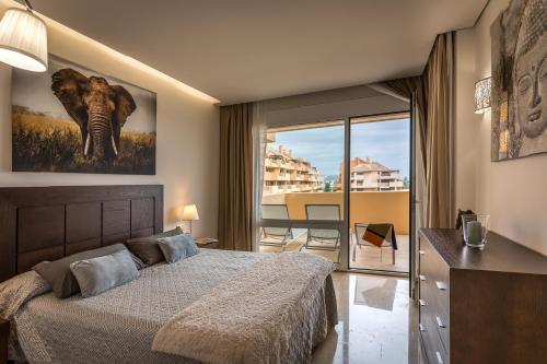 Un dormitorio con una cama y vista a un balcón. en Sotogrande - Ribera del Marlín, en Sotogrande