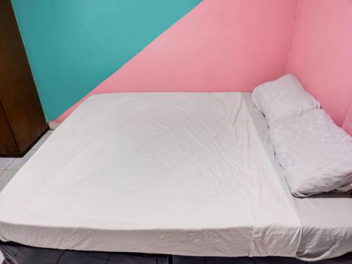 a bed in a room with a pink wall at SPOT ON 91781 Solo Baru Homestay Syariah in Jodoh