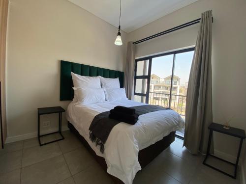 a bedroom with a bed and a large window at Penthouse in Waterfall with backup power in Midrand