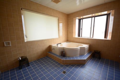 ein großes Bad mit einer Badewanne und einem Fenster in der Unterkunft Designer's Hotel Nakadoma Inn - Vacation STAY 32540v in Maeganeku