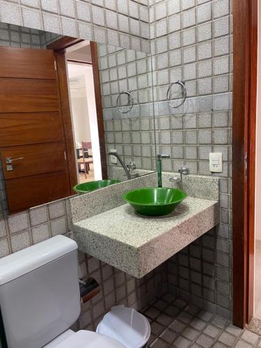 uma casa de banho com um lavatório verde e um WC em Casa da Jana com piscina em Porto Seguro
