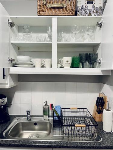 a kitchen sink with plates and dishes on shelves at Centrally Located a Home from Home - Free Parking in Kent