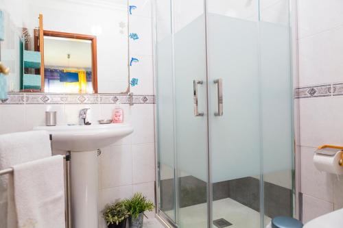 a bathroom with a glass shower and a sink at Quarto junto ao mar in Matosinhos