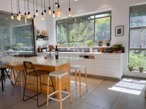 a kitchen with a table and chairs and windows at חופשה בחורשה in Sha'al