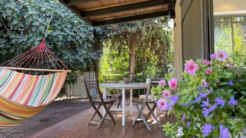 a patio with a hammock and a table and chairs at חופשה בחורשה in Sha'al