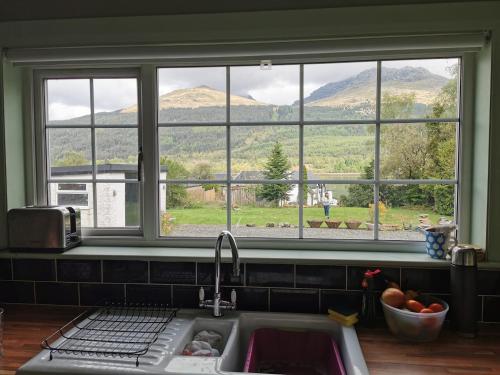 a kitchen sink with a view of mountains from a window at Arrochar Fern Cottage with Wood Burner & Loch View in Arrochar