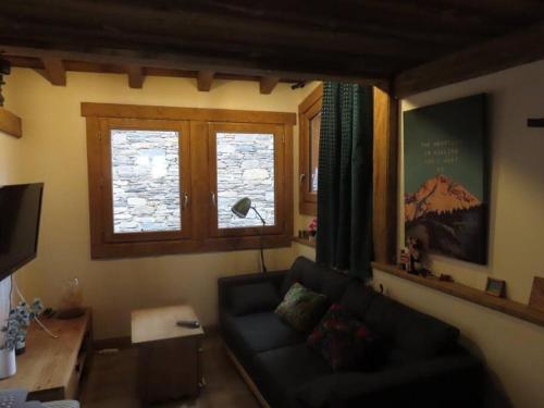 a living room with a couch and two windows at Authentique Maison de Village Savoyarde in Saint-Martin-de-Belleville